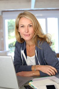 Middle aged blond woman at home with laptop