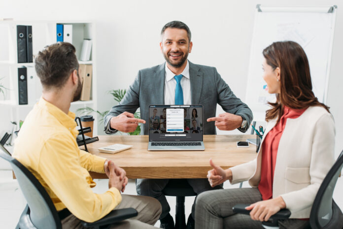 10 ways to introduce people on linkedin picture of man pointing to linkedin on computer sitting between two people