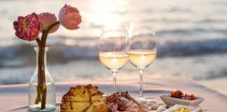 Romantic tray prepared with snacks, two glasses of white wine, and pink roses with ocean in background most romantic hotels in USA