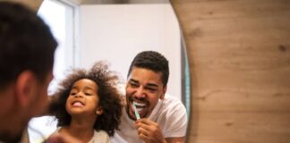 african american girl brushing teeth with dad.