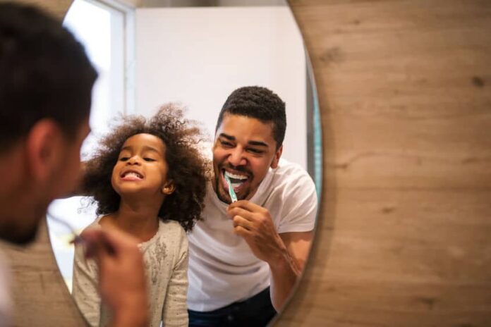 african american girl brushing teeth with dad.