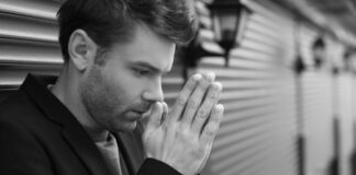 black and white photo of a guy with closed palms