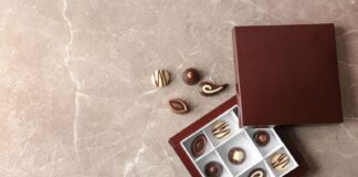 Box with different tasty chocolate candies on table, top view