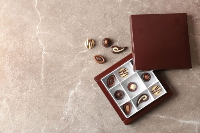 Box with different tasty chocolate candies on table, top view