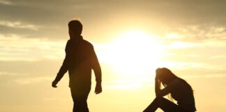 Couple silhouette breaking up a relation on the beach at sunset