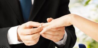 man in black suit proposing to a woman giving her an engagement ring