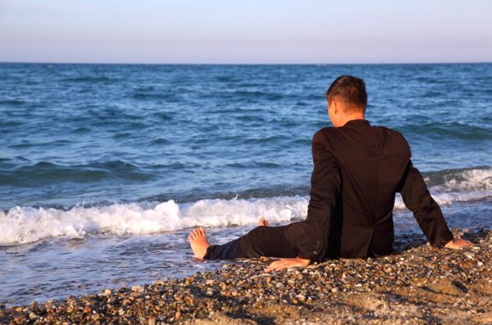 lonely man sitting at the beach