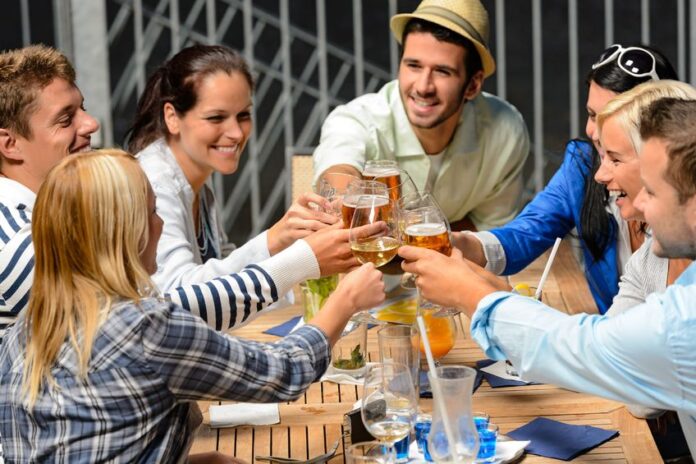 young people celebrating outside and drinking wine