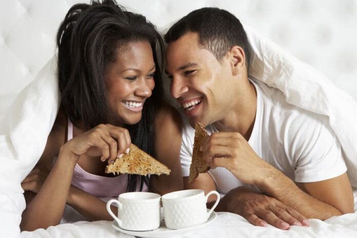 couple eating breakfast together on bed