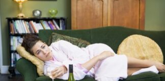 upset woman lying on the couch with a glass of wine