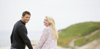 young couple holding hands while walking on the beach