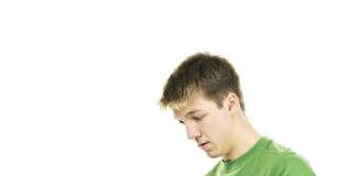 Serious young man sitting with laptop computer isolated on white background