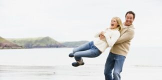 man happily carrying his woman at the beach