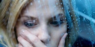 a woman holding her face sitting near the window