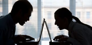 a silhouette of a man and woman on their laptops facing each other