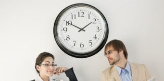 work colleagues talking under clock, drinking water