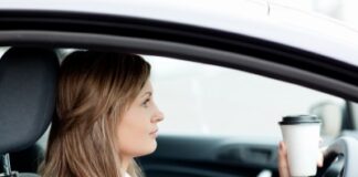 woman stopping her car while sipping coffee, checking her phone