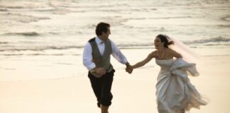 groom and bride running barefoot on beach