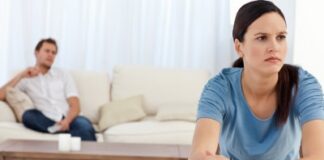 Angry woman doing her account while boyfriend relaxed on the sofa