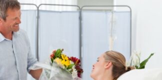 husband gives flowers to his wife at the hospital