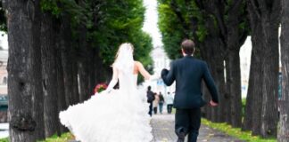 bride and groom running with joined hands on city park road