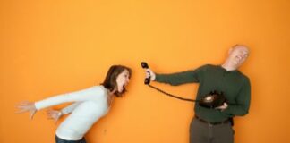 Man holds telephone while angry woman shouts into it