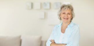 Portrait of a happy senior woman with hands folded relaxing on sofa at home