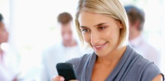 Closeup of beautiful woman reading text message with team in background