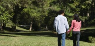 Couple holding hands walking and talking in park