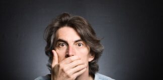 a surprised man hiding his mouth by his hand