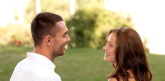 young couple smiling, looking at each other, sitting on a bench