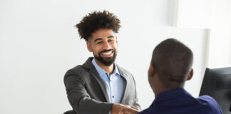 Smiling Young Businessman Shaking Hand With Male Candidate In Office
