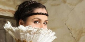 beautiful woman covering half of her face with a white fan like lace