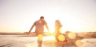 A happy couple runs on a beach after practicing self care in marriage