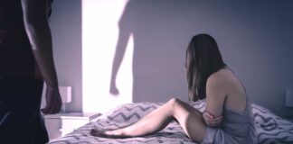 A woman in an unhealthy relationship sits on a bed after reading toxic relationship quotes