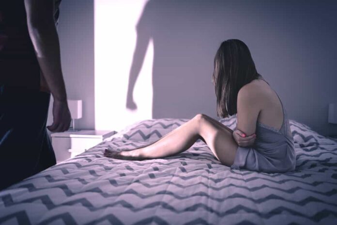 A woman in an unhealthy relationship sits on a bed after reading toxic relationship quotes