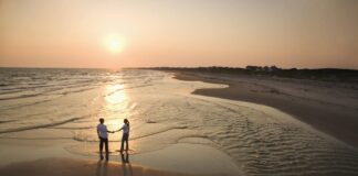 A couple holds hands on the beach on one of the most romantic getaways in North Carolina