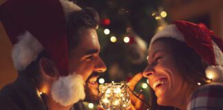 christmas date ideas - photo of couple smilin in front of lit christmas tree