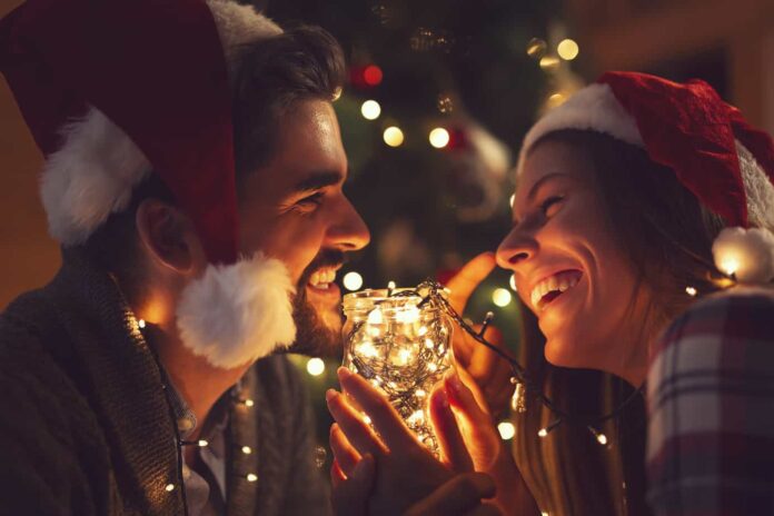 christmas date ideas - photo of couple smilin in front of lit christmas tree