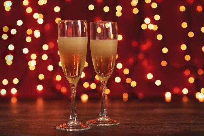 new year's eve date ideas header image - two champagne glasses side by side in front of red background with white lights