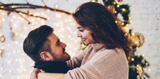 A couple embrace after she reads romantic Christmas messages for her