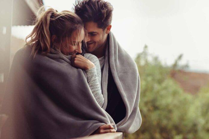 when you meet the right person header image - photo of cute couple wrapped up together in gray blanket. standing outside on cloudy day