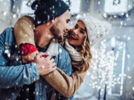 A couple embraces in the snow on one of the most romantic winter getaways