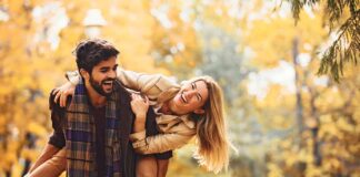 conversation starters for couples image - couple playing in the autumn, blond woman taking piggyback ride from bearded man