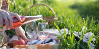 romantic things to do in provence france - image of picnic set up in green grass, rose wine being poured. cheese sits on charcuterie board