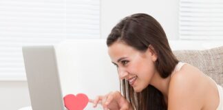 woman on a couch looking at her laptop and smiling
