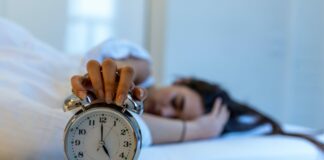 woman turning off an alarm clock