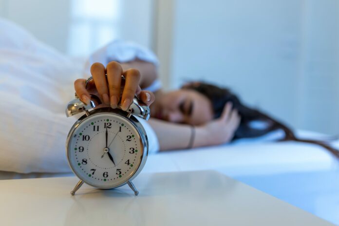 woman turning off an alarm clock