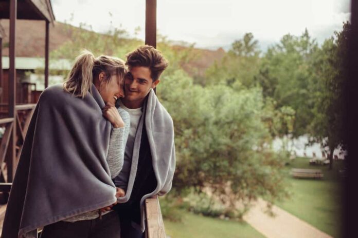 A couple embraces one another while sharing a blanket and asking deep questions to ask your boyfriend.